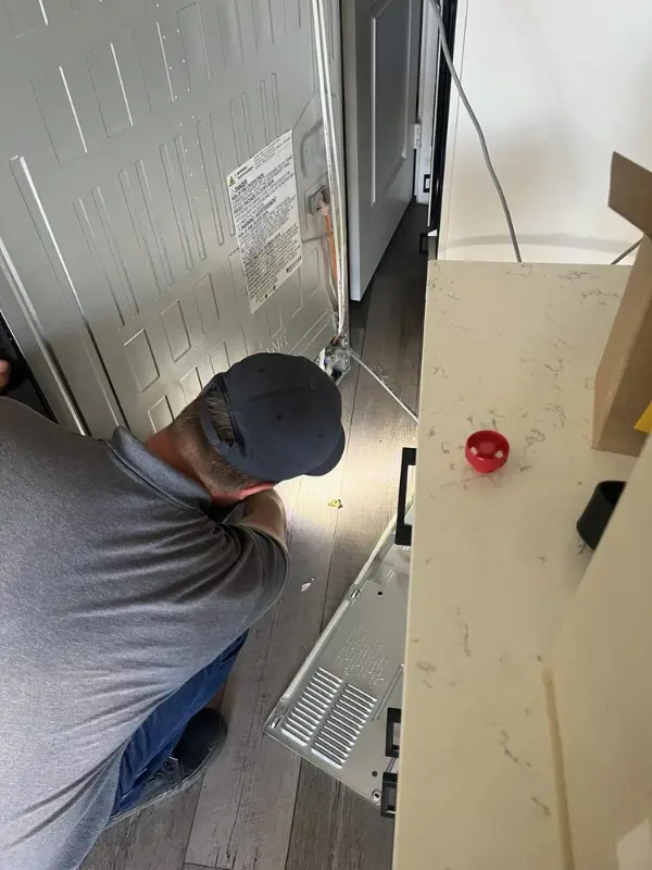 Tech working on the back of a refrigerator in a Las Vegas kitchen
