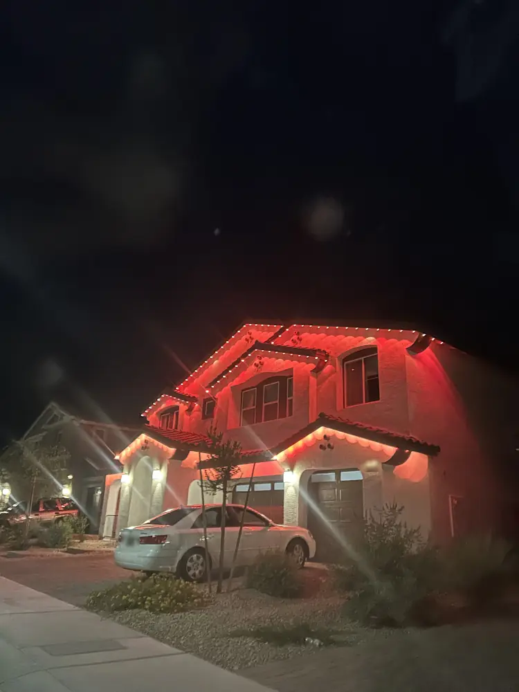 Side view of permanent eave lighting in warm orange on a two-story stucco home at night, Las Vegas
